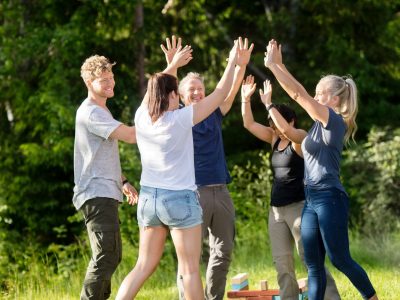 Happy male and female friends in casuals giving high-five after playing with building blocks in forest